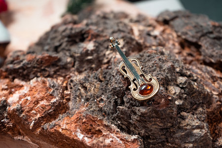 Decoration in the form of a violin of bronze and amber against the background of birch log