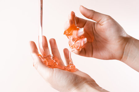 Liquid honey in the girls arms. Wax for depilation on a light pink backgroundの写真素材