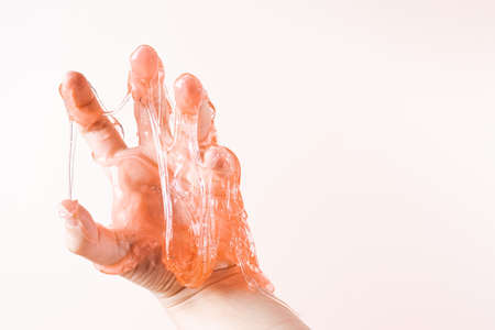 Liquid wax with thin threads spreads on the fingers of the womans hand close-up on a light beige...