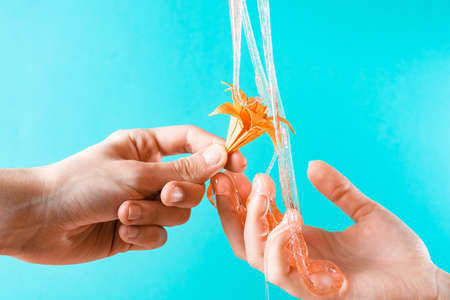 Honey flows into his arms, holding a paper flower on a blue background