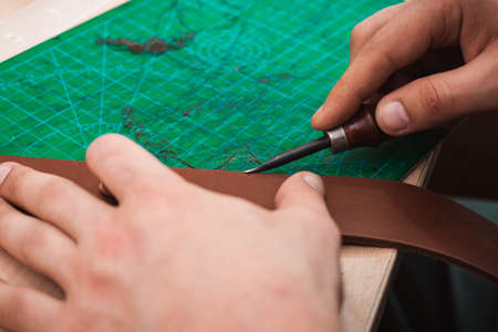 The leather master handles the edges of the belt blanks