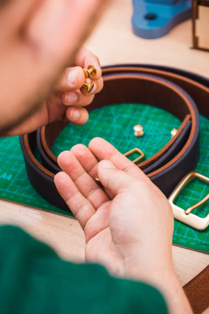 Golden rivets for a leather belt in the hands of a master