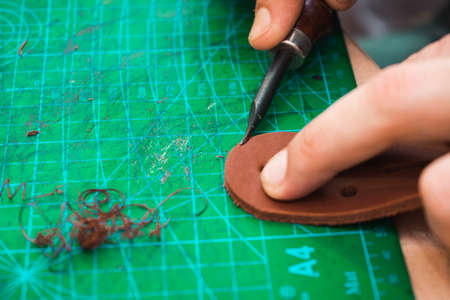 The leather master handles the edges of the belt blanks