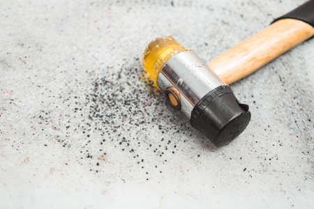 The hammer lies on a gray table with holes from blows