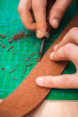 The leather master handles the edges of the belt blanks