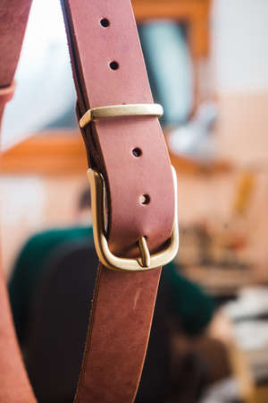 Brown belt hangs in the background of a working leather masterの写真素材