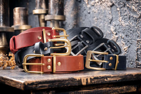 A bunch of leather straps lie on a wooden table