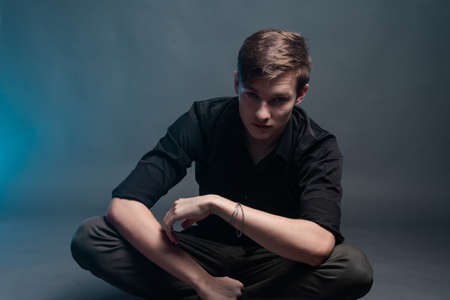 Portrait of a young man on a gray background with blue smokeの写真素材