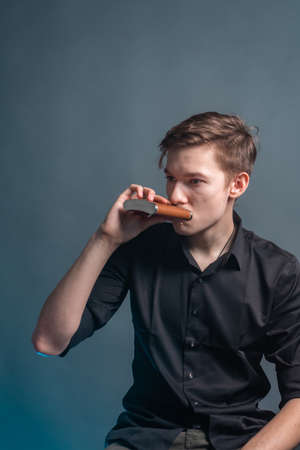 Guy drinks alcohol from a flask on a gray background