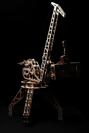 Wooden toy crane on a black background with a container