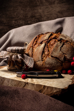 Knife lies next to bread and a jar of biscuits on a brown background