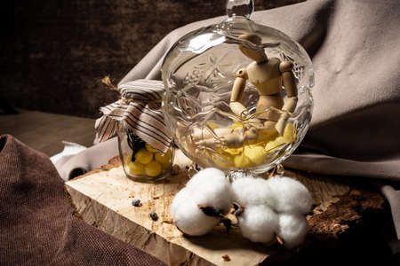 The mannequin for drawing lies in a vase with candy next to a jar with yellow sweets on a beige background.の写真素材