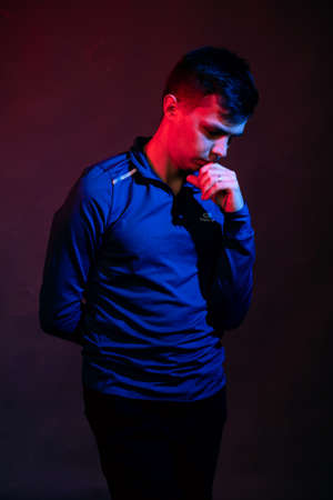 Emotions of a guy in a studio with blue and red light on a black background