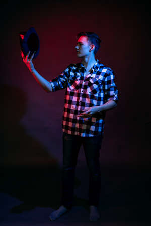 A guy in a plaid shirt with red and blue lighting in the studio on a black backgroundの写真素材