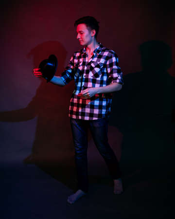 A guy in a plaid shirt with red and blue lighting in the studio on a black backgroundの写真素材
