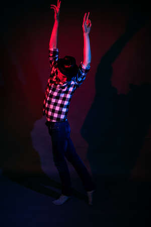A guy in a plaid shirt with red and blue lighting in the studio on a black backgroundの写真素材