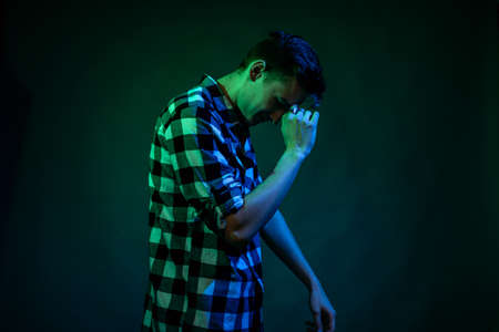 A young man dances in the studio with blue and green lightの写真素材