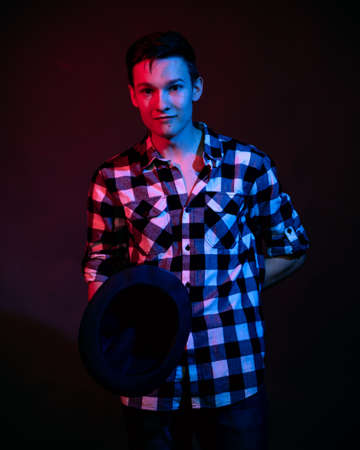 A young man in a studio on a dark background with a multicolored lightの写真素材