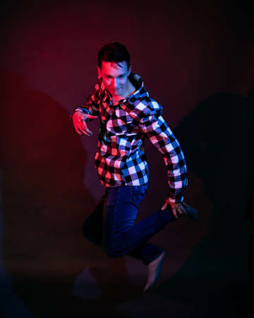 A guy in a plaid shirt with red and blue lighting in the studio on a black backgroundの写真素材