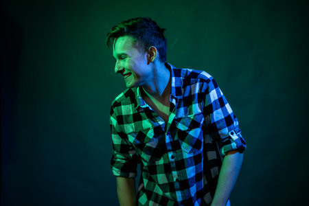 A young man dances in the studio with blue and green lightの写真素材
