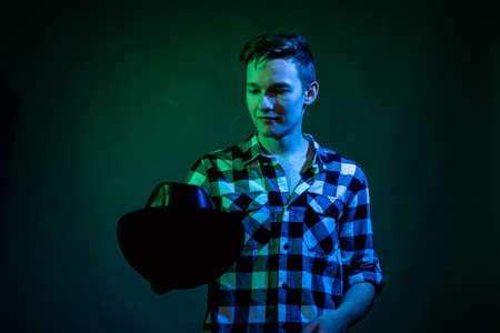 A young man dances in the studio with blue and green lightの写真素材