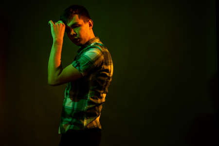 The guy in the checkered shirt dances, illuminated by orange and green lightの写真素材