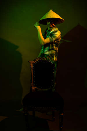 A guy in a plaid shirt and a Chinese hat on a dark backgroundの写真素材