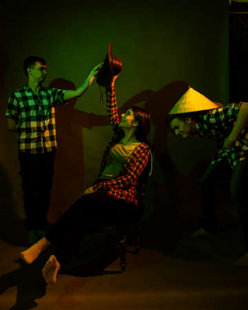 Two guys and a girl in plaid shirts in a studio with a multicolored lightの写真素材