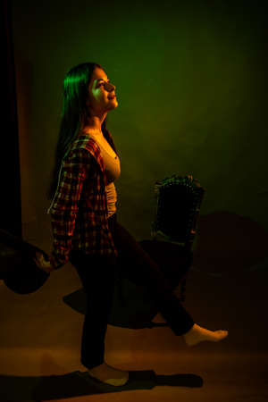 A girl in a plaid shirt with a cowboy hat illuminated by multicolored lightの写真素材