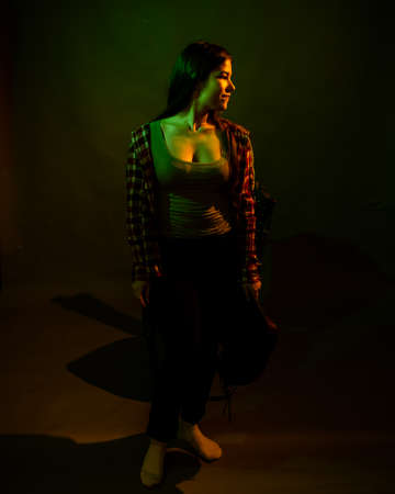 A girl in a plaid shirt with a cowboy hat illuminated by multicolored light