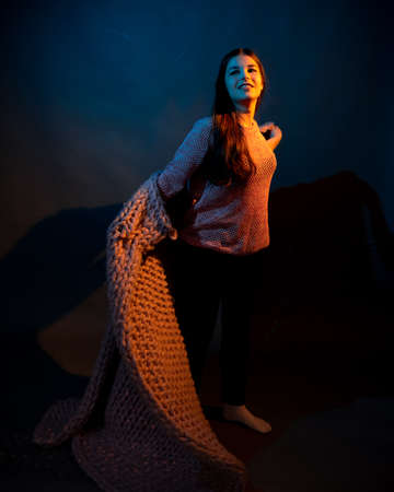 The girl dances with a pink plaid in her hands. illuminated by yellow and blue lightの写真素材