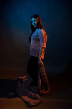 The girl dances with a pink plaid in her hands. illuminated by yellow and blue lightの写真素材