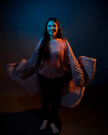 The girl dances with a pink plaid in her hands. illuminated by yellow and blue lightの写真素材