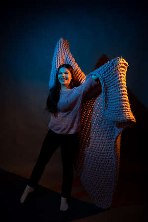 A girl in a pink sweater sits on the floor. plaid. illuminated by blue and yellow lightの写真素材