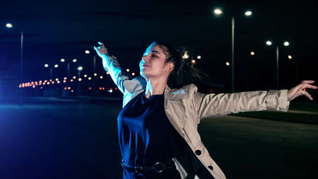 Girl in a coat in the parking lot against the backdrop of the night city with lanternsの写真素材