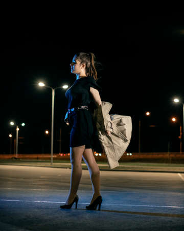 Young girl in a parking lot against the backdrop of the night cityの写真素材