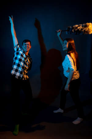 A guy in a plaid shirt and a girl with a dust brush against a dark backgroundの写真素材