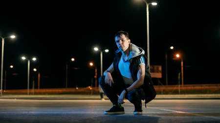 The guy sits in the parking lot at night under the lights of the lanternsの写真素材
