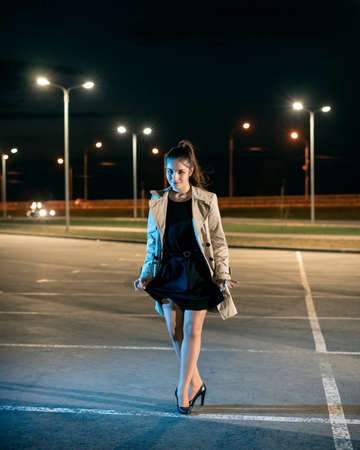 Young girl in a parking lot against the backdrop of the night cityの写真素材