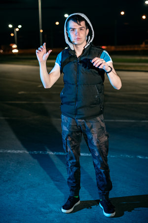 Guy at night in the parking lot against the background of lanterns