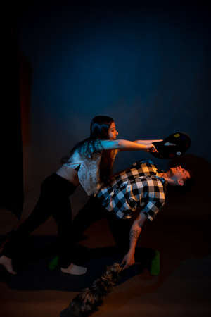 A girl paints a guy in the studio on a dark background illuminated by multicolored lightの写真素材