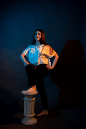 Girl on a stand on a dark background with multicolored lightの写真素材