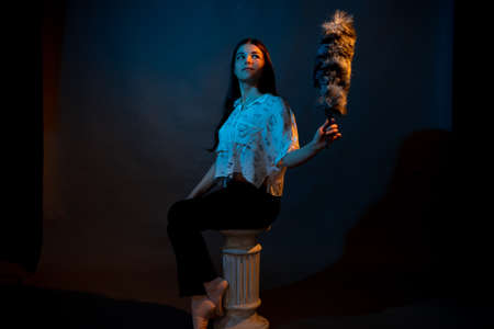 A girl stands on a miniature Greek column illuminated by multicolored lightの写真素材