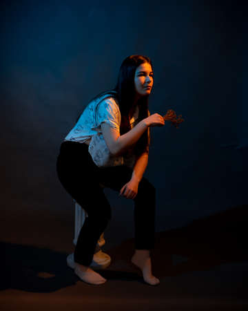 Girl on a stand on a dark background with multicolored lightの写真素材