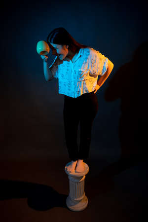 Girl on a stand on a dark background with multicolored lightの写真素材