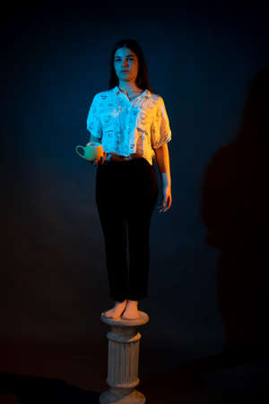 Girl on a stand on a dark background with multicolored lightの写真素材