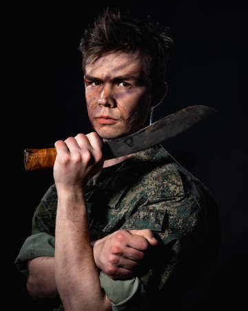 Portrait of a soldier with scars and combat coloring, holding a machete in the urns on a black backgroundの写真素材