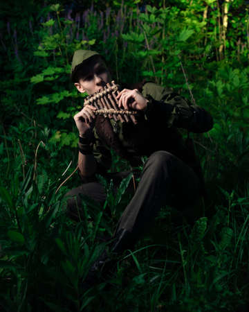 Peter Pan plays a flat sitting in the grass against the backdrop of the forest. Cosplay on Peter Foam. Robin Hoodの写真素材