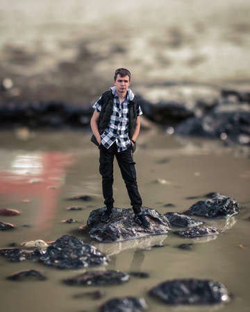 A little man stands on a rock in the middle of a puddleの写真素材