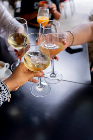 Close-up of people hands clinking glasses with white wine at barの写真素材